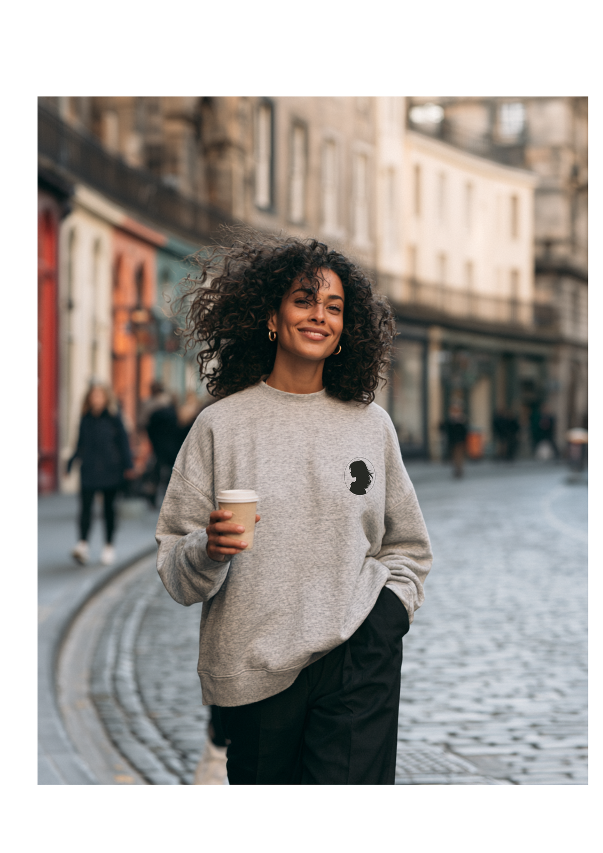 Woman with a coffee on Edinburgh cobbles in the Cameo sweatshirt