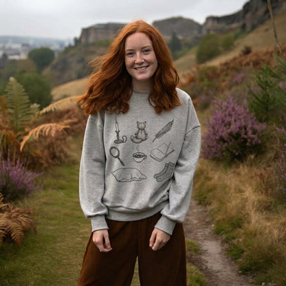 Woman on a Scottish hillside in the Curiosities sweatshirt in light grey marl